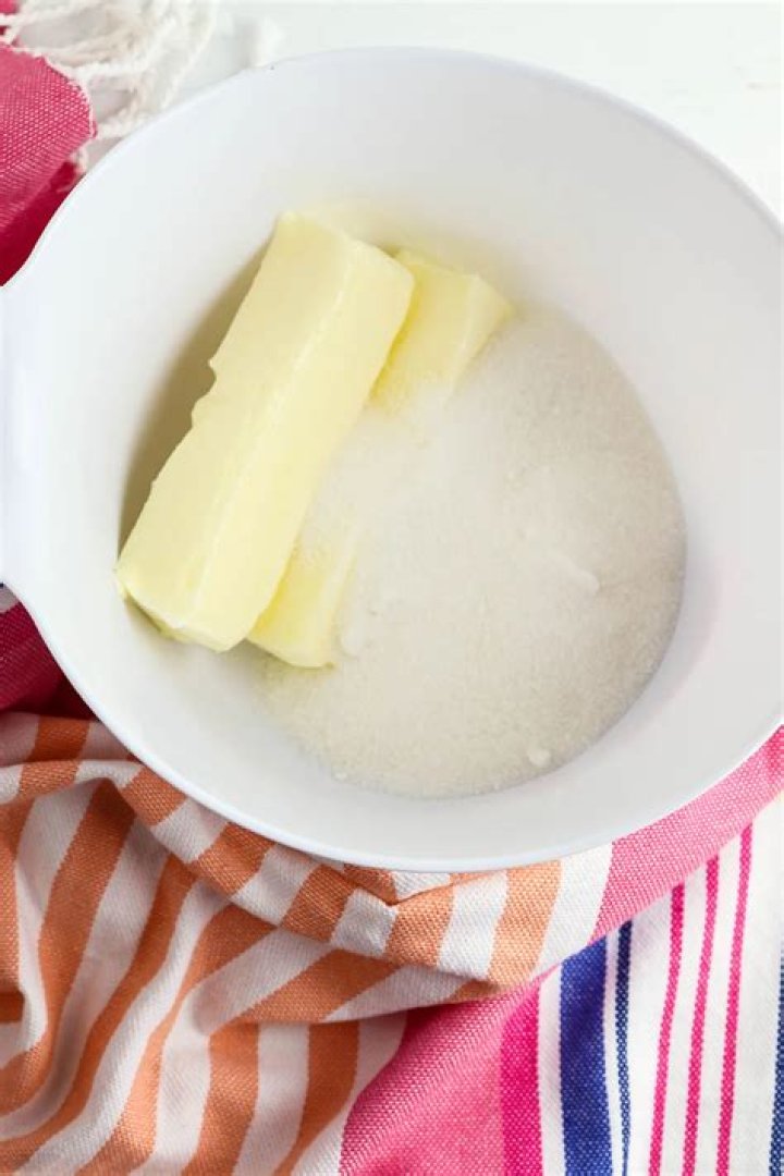 Butter and sugar in a glass mixing bowl.