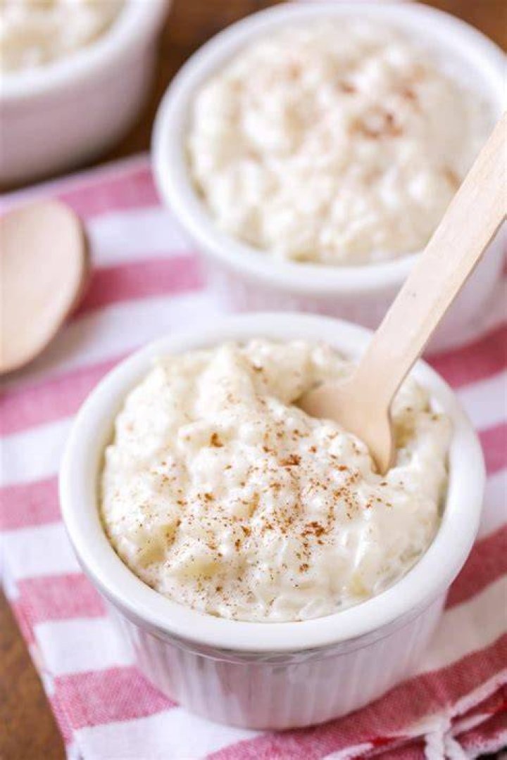Rice pudding in a white bowl topped with ice cream and cinnamon.